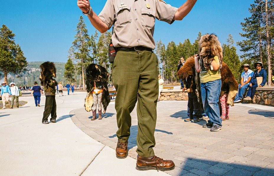 photo of park ranger with arms raised in front of several people wearing faux bear heads during talk
