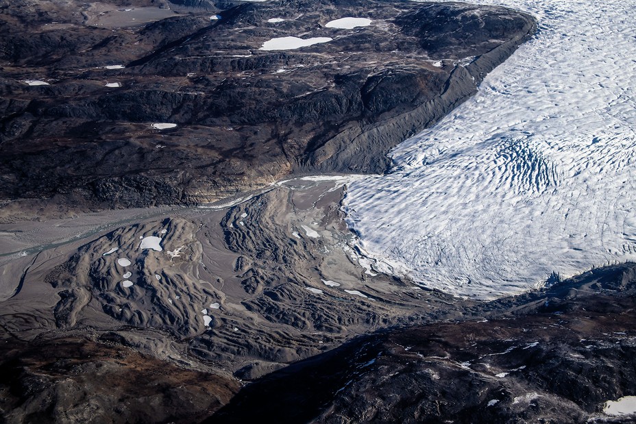 aerial photo of valley with curving glacier covering right half and exposed rock ridges at left