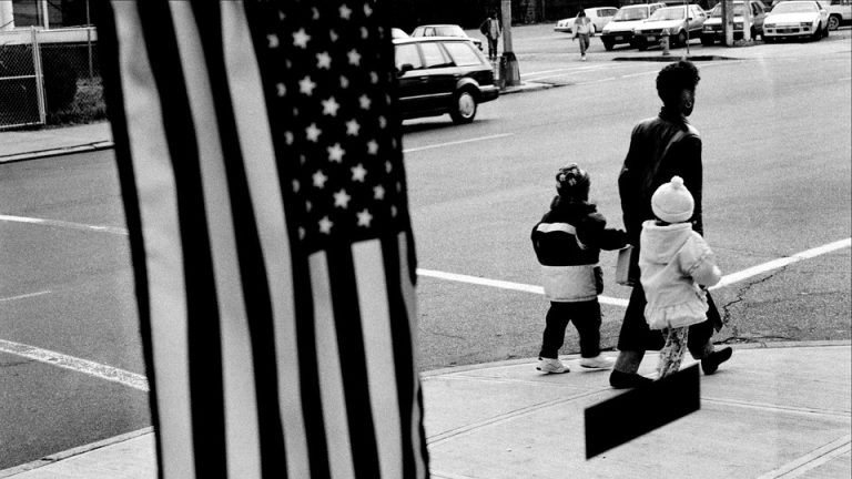 a mother and children walking in front of an American flag