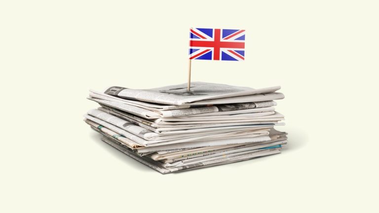 A pile of newspapers with a British flag planted on top