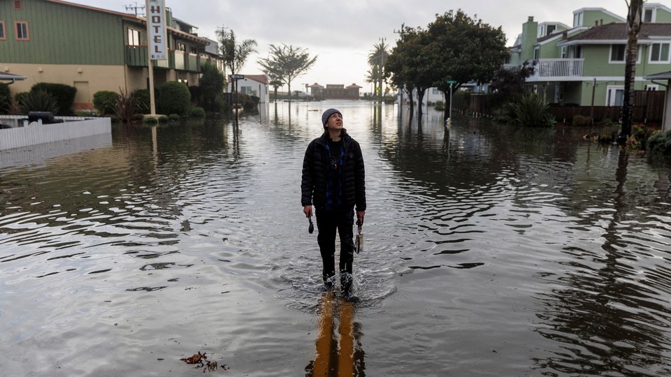 A resident walks along a flooded street after rainstorms slammed northern California, in the coastal town of Aptos, on January 5, 2023