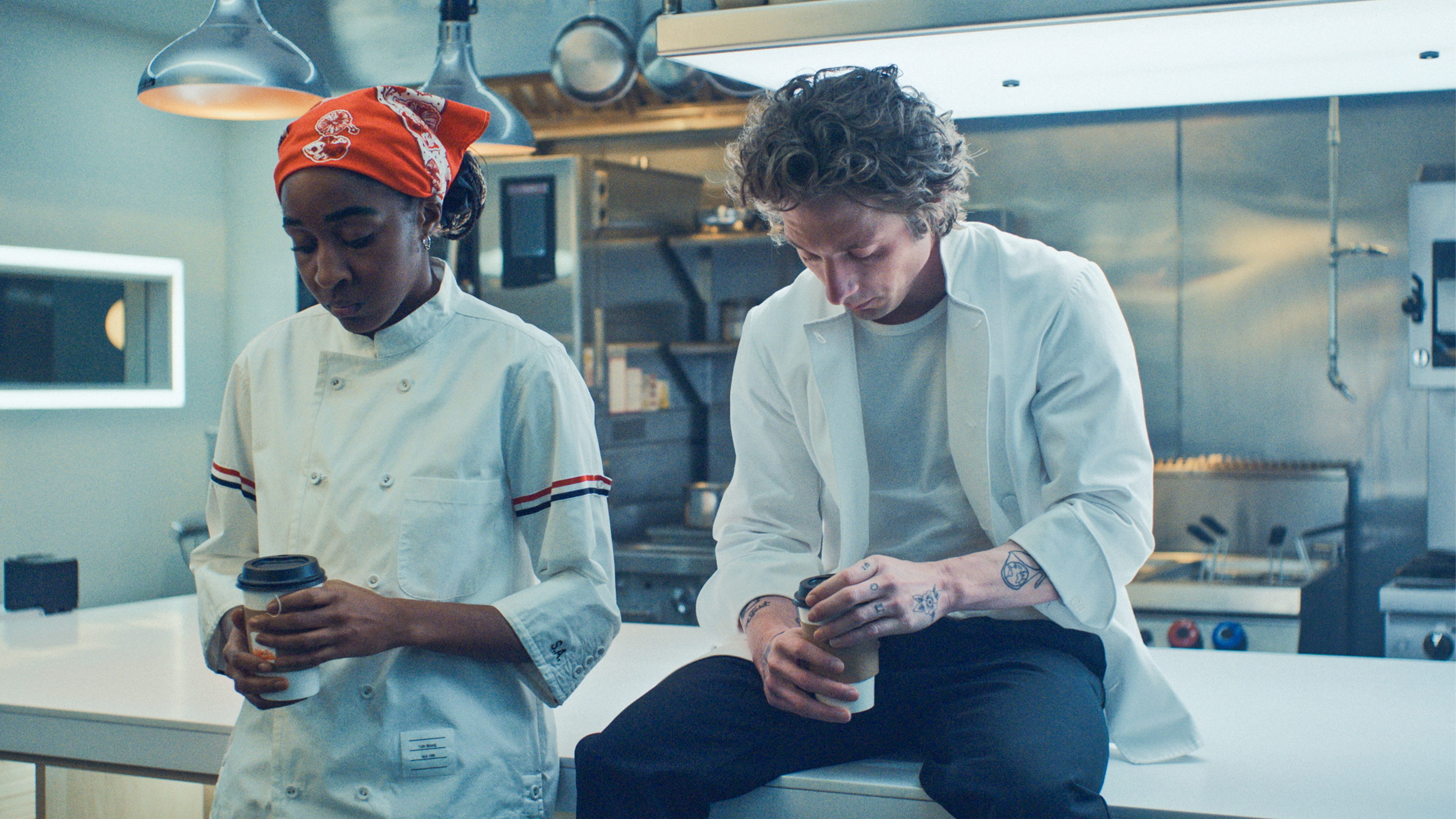 Ayo Edebiri and Jeremy Allen White next to each other holding coffee cups