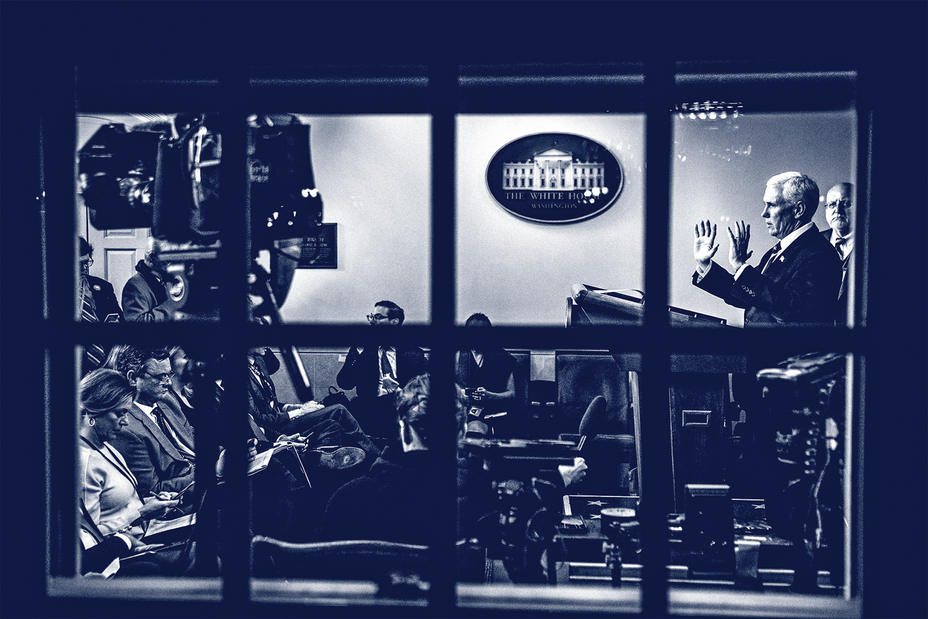 photo looking in through window at press room with man speaking and gesturing at lectern with camera and audience