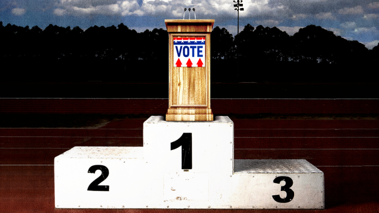 A dais with a "vote" sign sitting atop a winner's podium on a running track