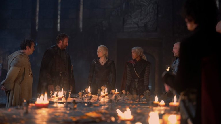 Rhaenyra and her war council standing around a table lit with candles