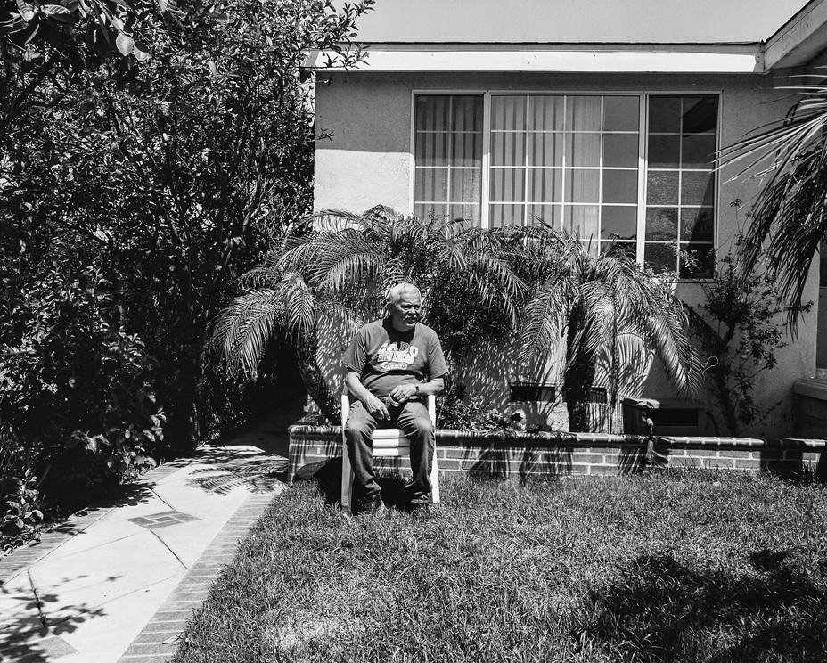 Picture of Gustavo Hernandez, 66, sitting for a portrait in front of his home, which is adjacent to oil pipelines buried underneath the soil and the Phillips 66 refinery.