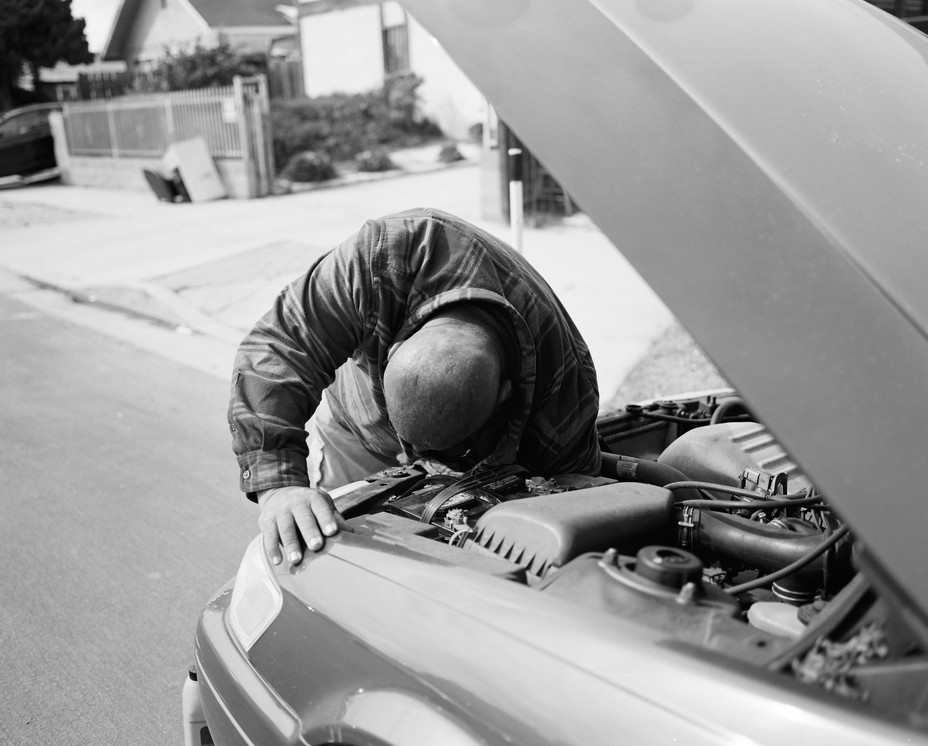 Juan Sandoval, 52, who lives near Drumm Avenue, a-once residential street that has been converted into a main truck route, changes the fluids to a neighbors car.