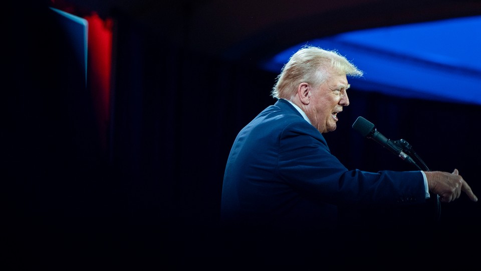 Donald Trump speaking into a microphone, gesturing his right arm forward