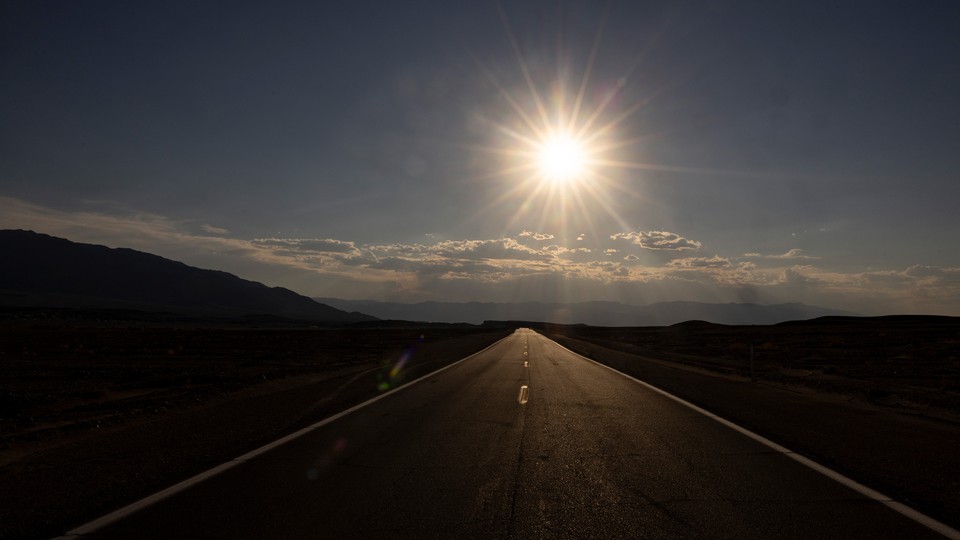 Photo of a low sun above a long road