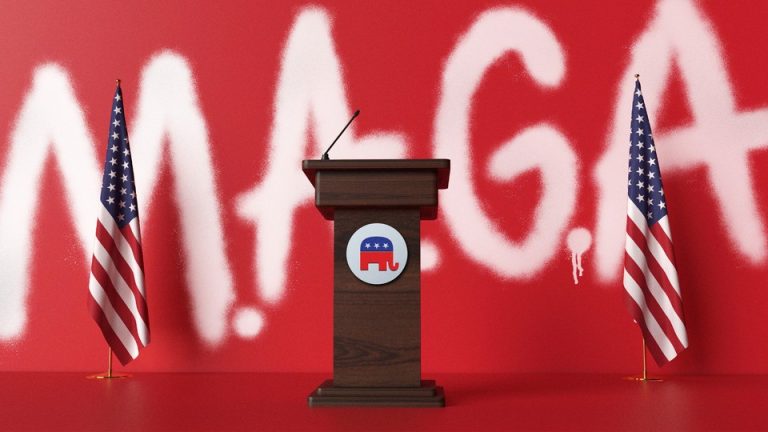 podium with American flags and "MAGA" in spraypaint in background