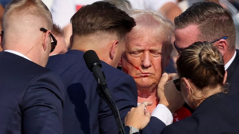 Donald Trump with blood on his face, surrounded by Secret Service agents