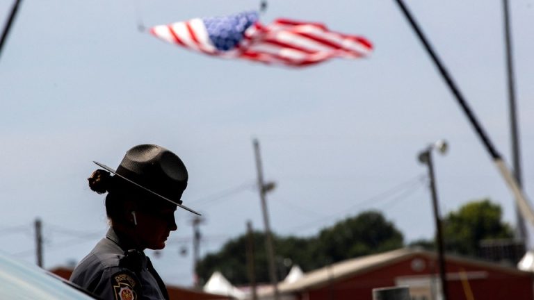 A state trooper stands next to a vehicle blocking a road leading to the event grounds in Butler, Pennsylvania,