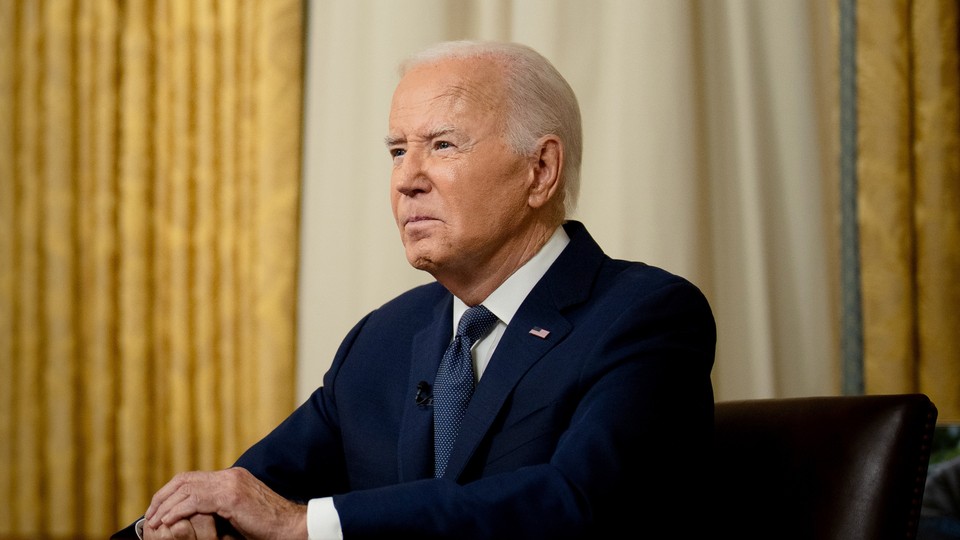 Joe Biden sits at a desk in the Oval Office