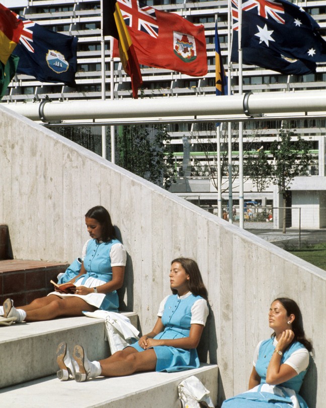 Three girls sitting and reading under three flags