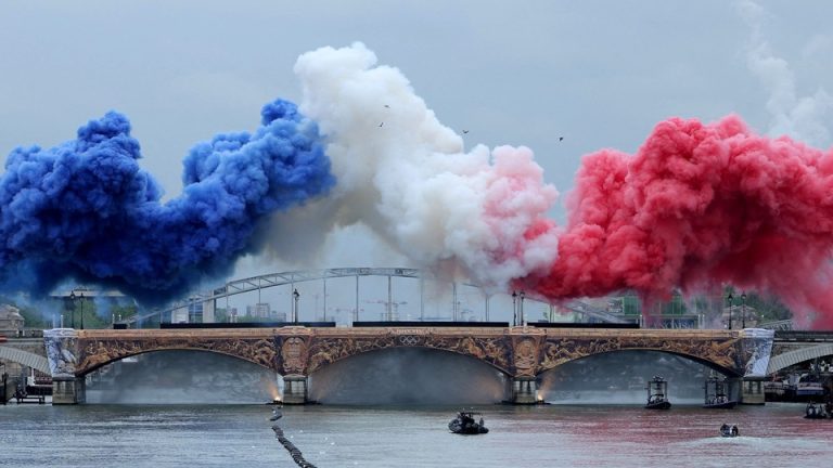 blue, white, and red plumes of smoke above a bridge over the Seine