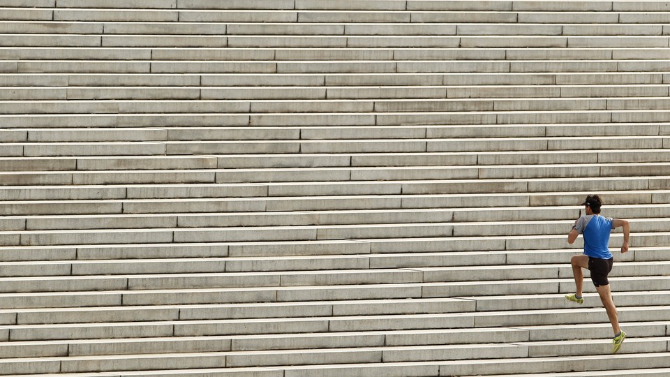 A man in athletic clothing runs up a long flight of stairs