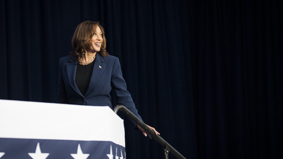 Kamala Harris smiles and walks up steps at a campaign event