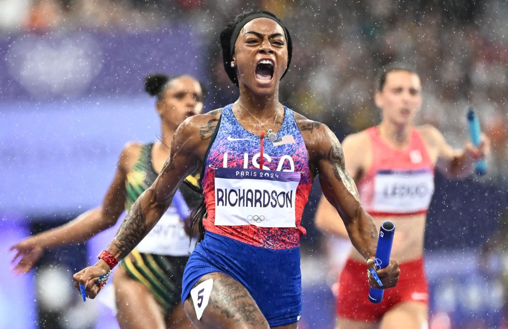 A runner reacts as she crosses the finish line of a race first, in the rain.