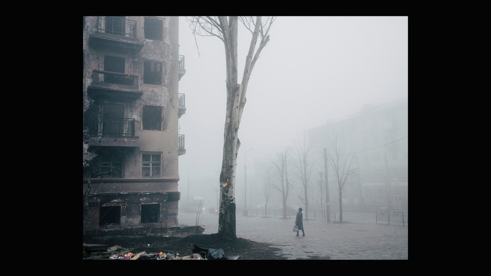 A woman walks past a destroyed building in Mariupol.