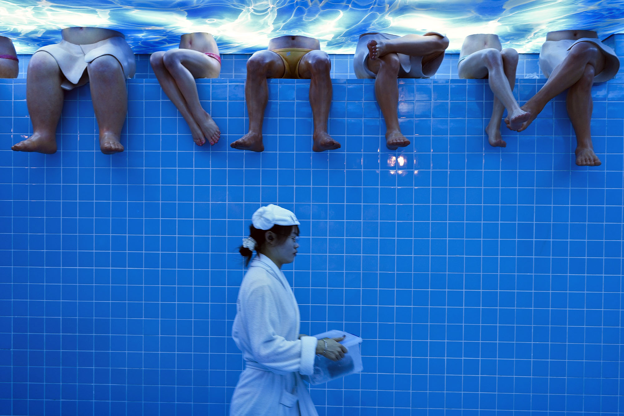 A waitress walks by mannequins at a restaurant set up to look like a bathing center, inside a shopping mall in Beijing.