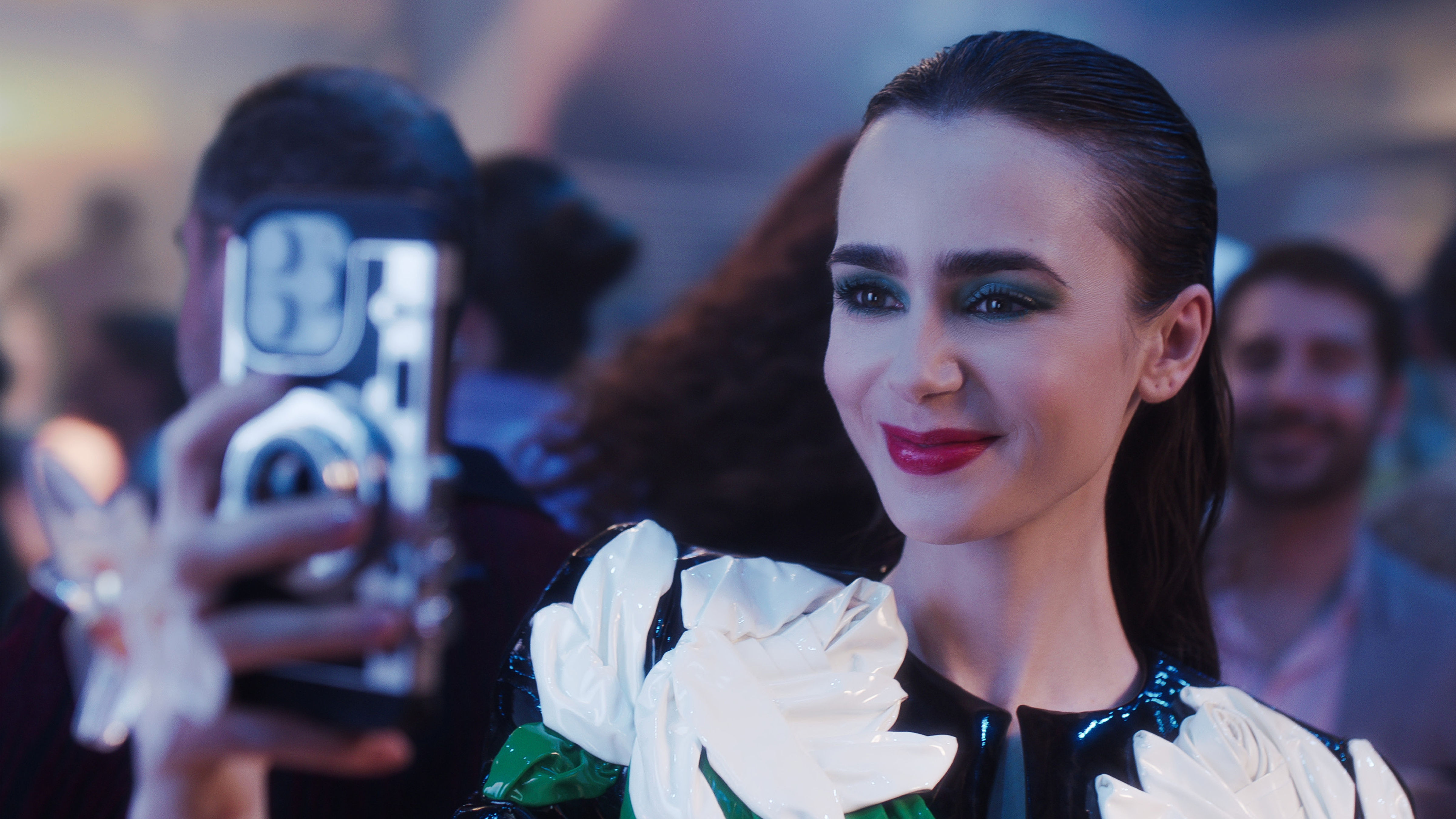 Lily Collins smiles while taking a selfie in an episode of Emily in Paris