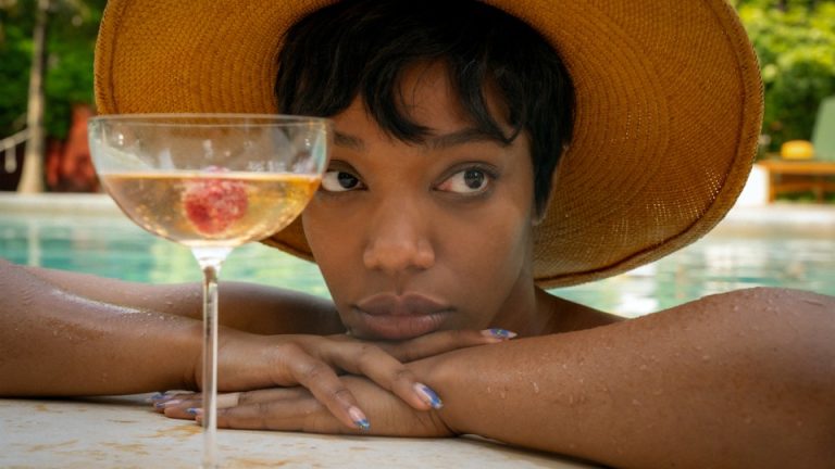 Naomi Ackie peering over the side of a pool next to a cocktail