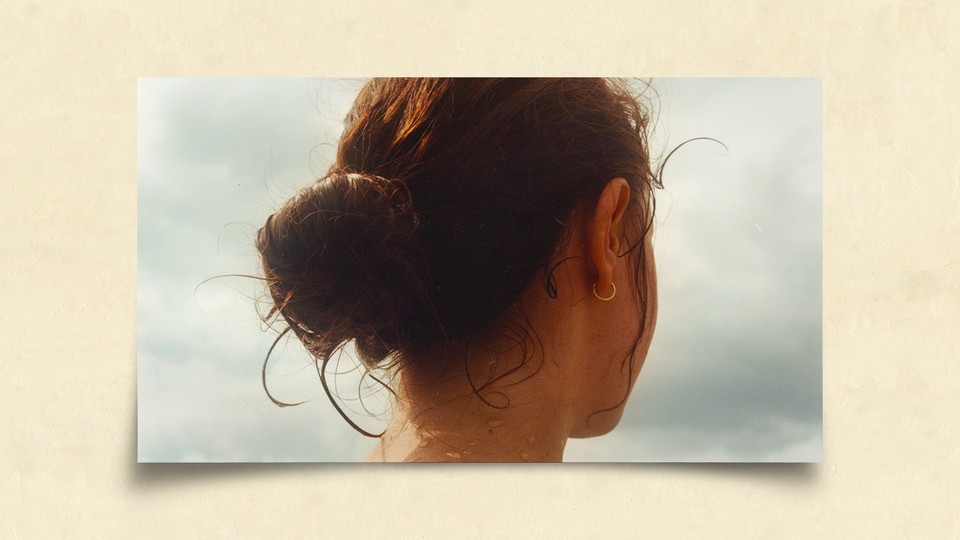 Image of the back of a girl's head as she looks towards the coast