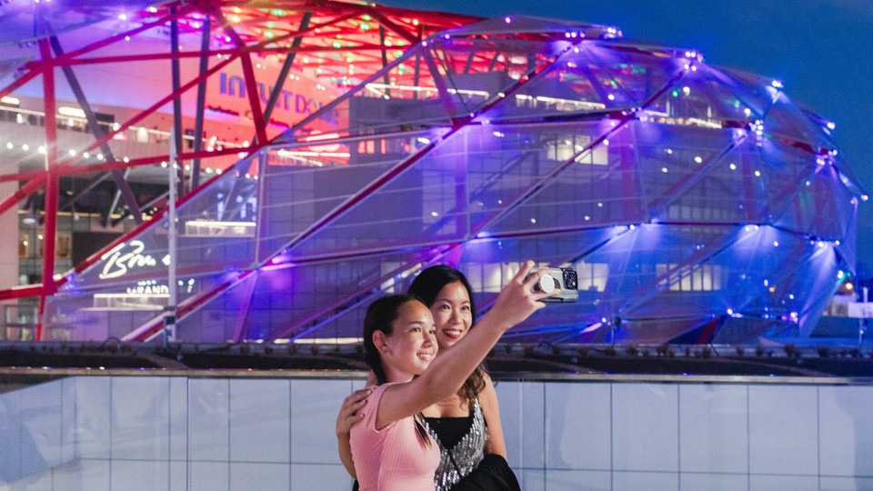 Two women take a selfie in front of the Intuit Dome.