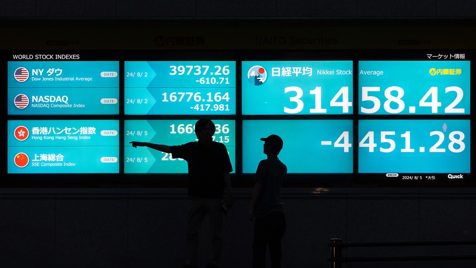 A photo of two people silhouetted against a digital display that shows falling stock indexes