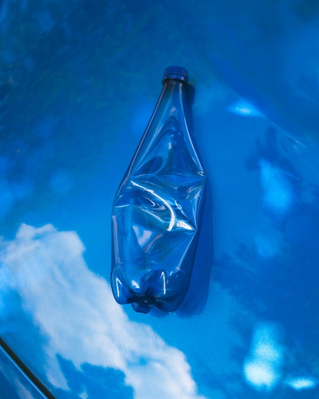 a squished, empty plastic water bottle on the hood of a blue car