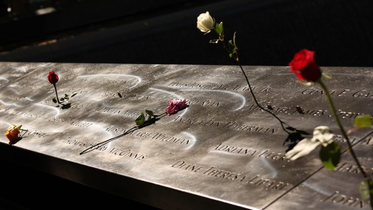 A part of the 9/11 memorial with flowers over it