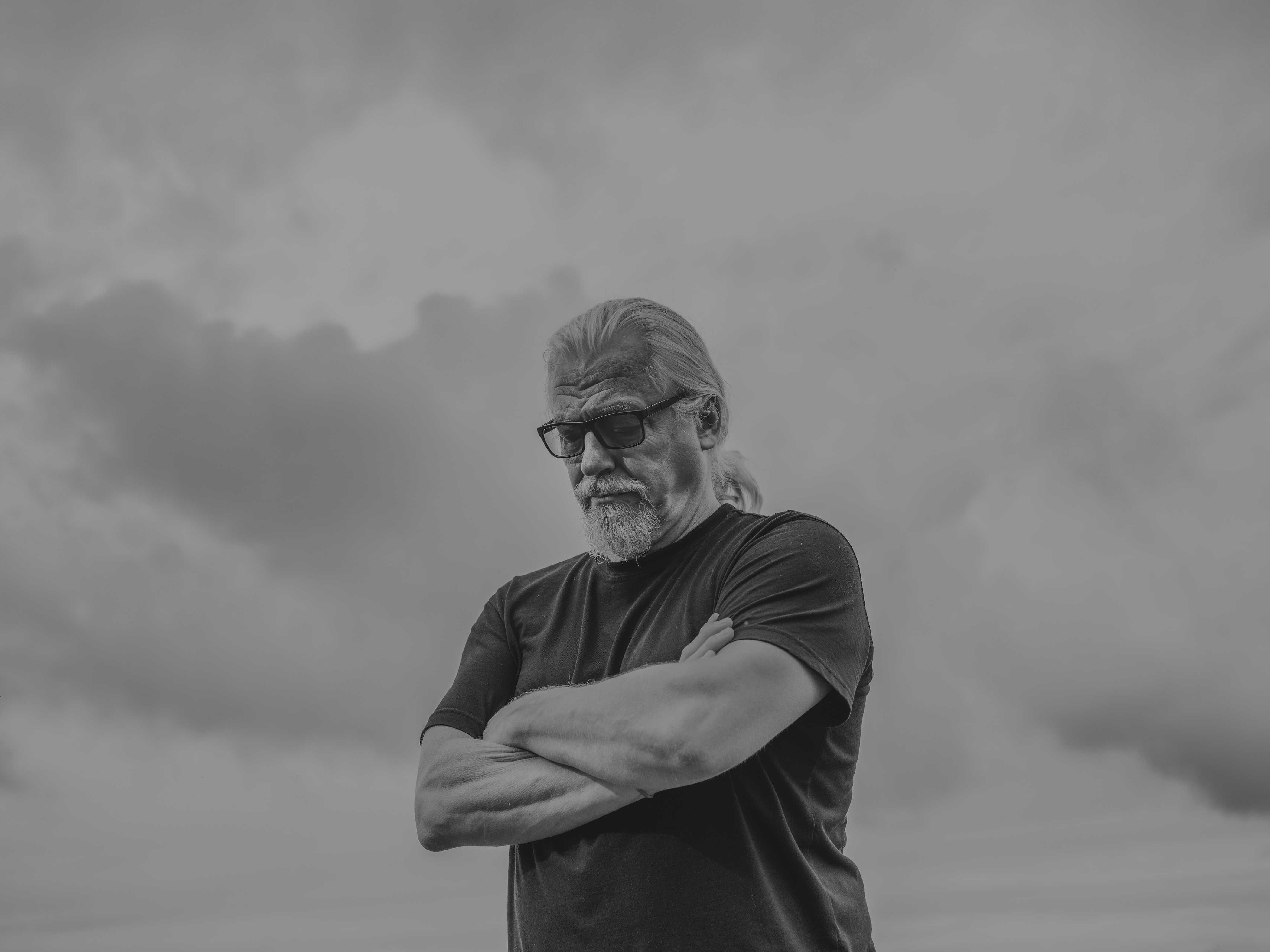 a man looking down with sky behind him