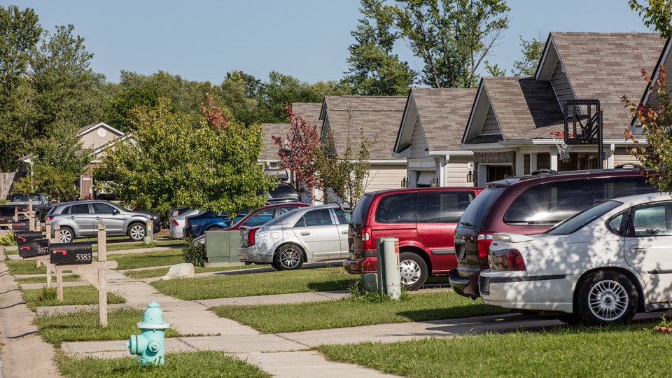 A photo from 2016 of various kind of cars in people's driveways on a suburban street