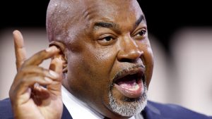 A color photograph of Mark Robinson speaking, and gesturing upward with his right hand