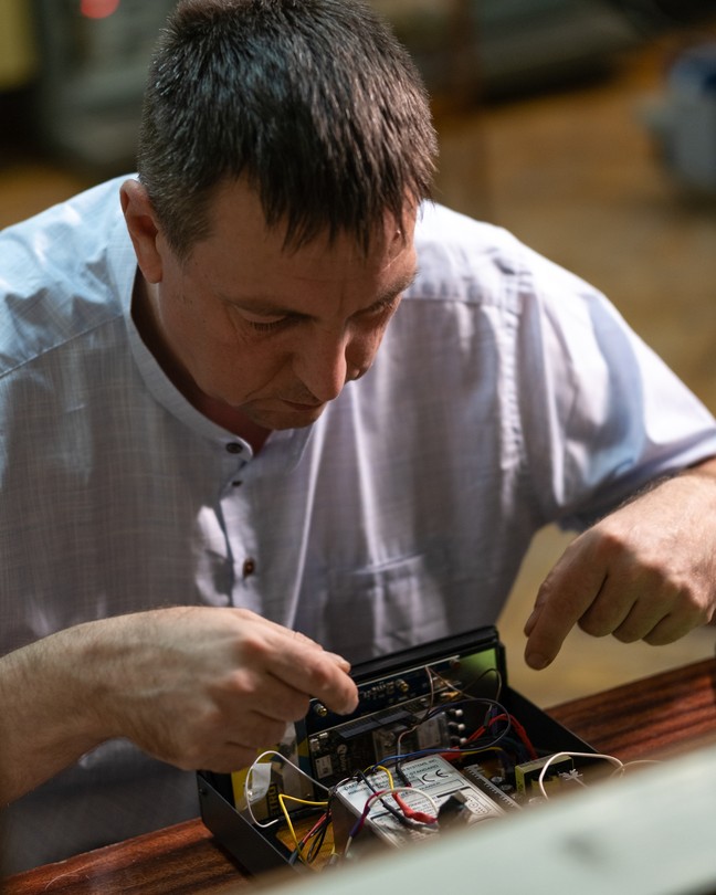 A man works on a piece of equipment with wires.