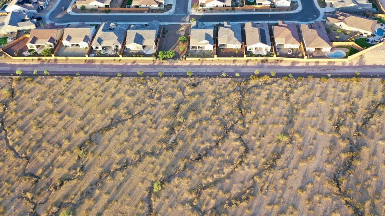 A color aerial photograph of desert landscape abutting a suburban neighborhood