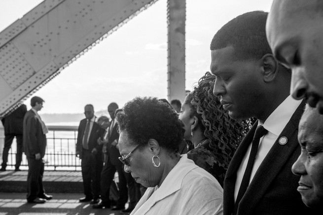 black and white image of Michael Regan praying alongside community members in Selma, Alabama