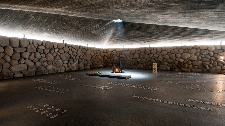 A gray floor inscribed with names surrounded by a stone wall with a pyramidal roof.