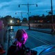 A woman looks at a car next to an ambulance and a flooded tunnel