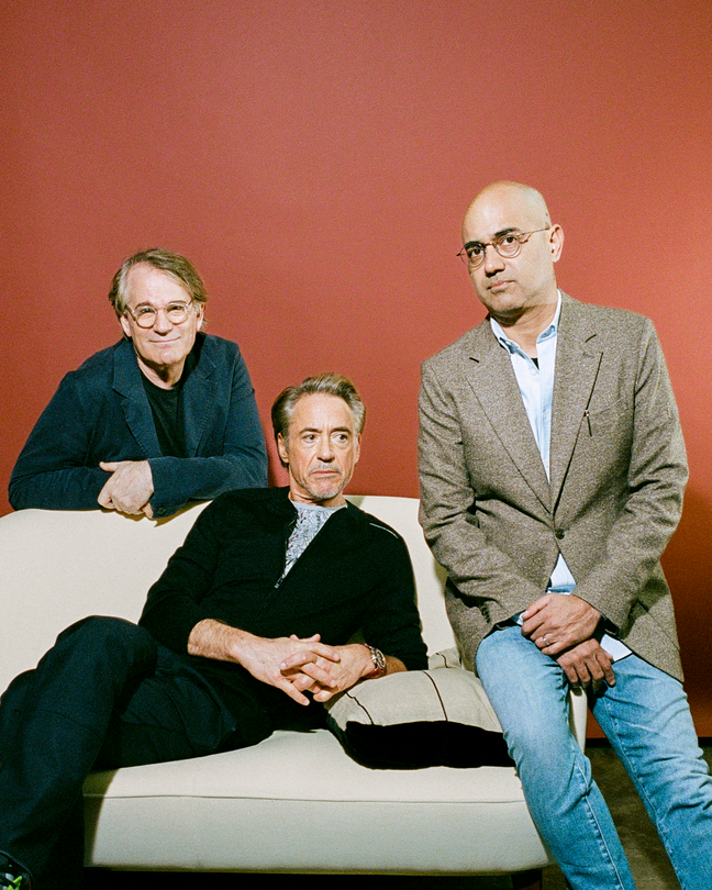 photo of Robert Downey Jr. sitting on beige sofa, flanked by Bartlett Sher in glasses and blue-green blazer on left and Ayad Akhtar in glasses and tan blazer on right