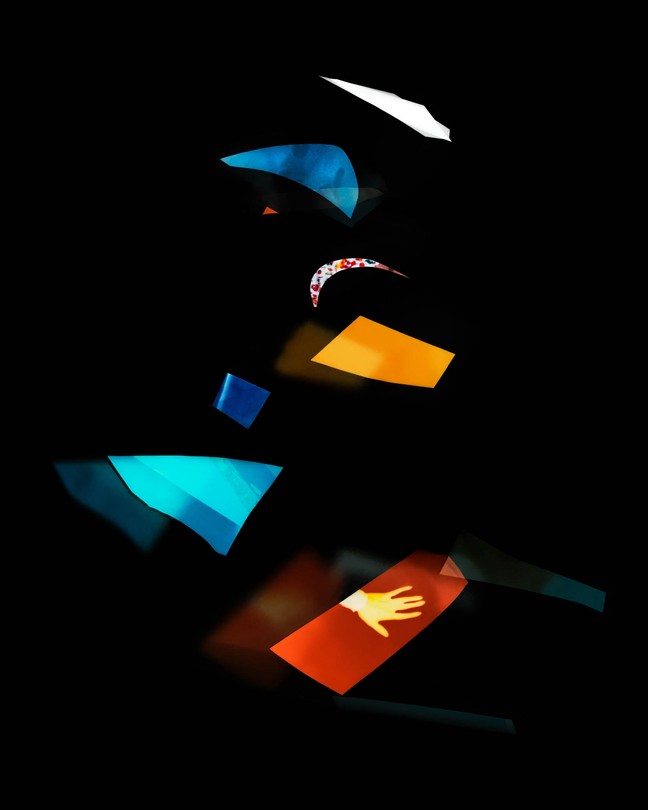 fragments of bright color against a black background; one of them has a silhouette of a hand within it