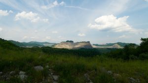 a field of grass and a rock formation in the distance, under a wide blue sky