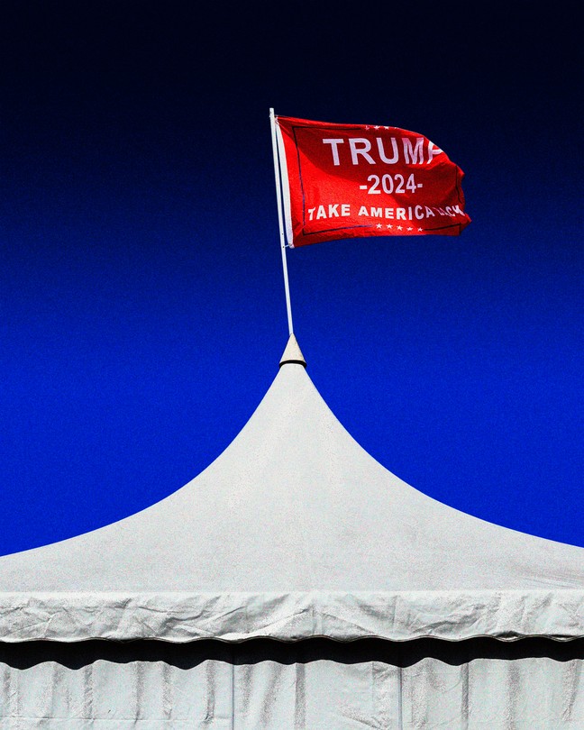 A color photograph of a white pointed tent top with a red "Trump 2024" flag on top