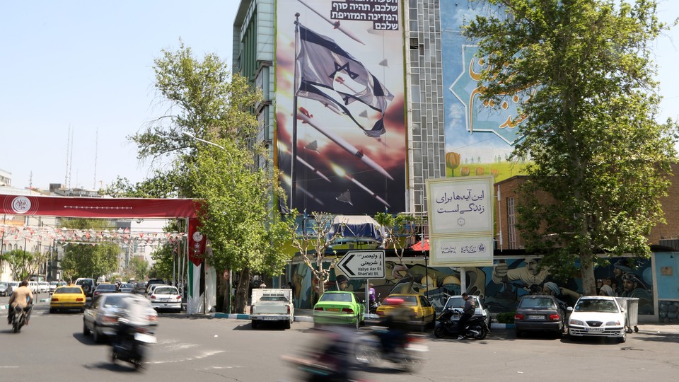 On a street in Tehran, anti-Israel banners cover the side of a high rise building.