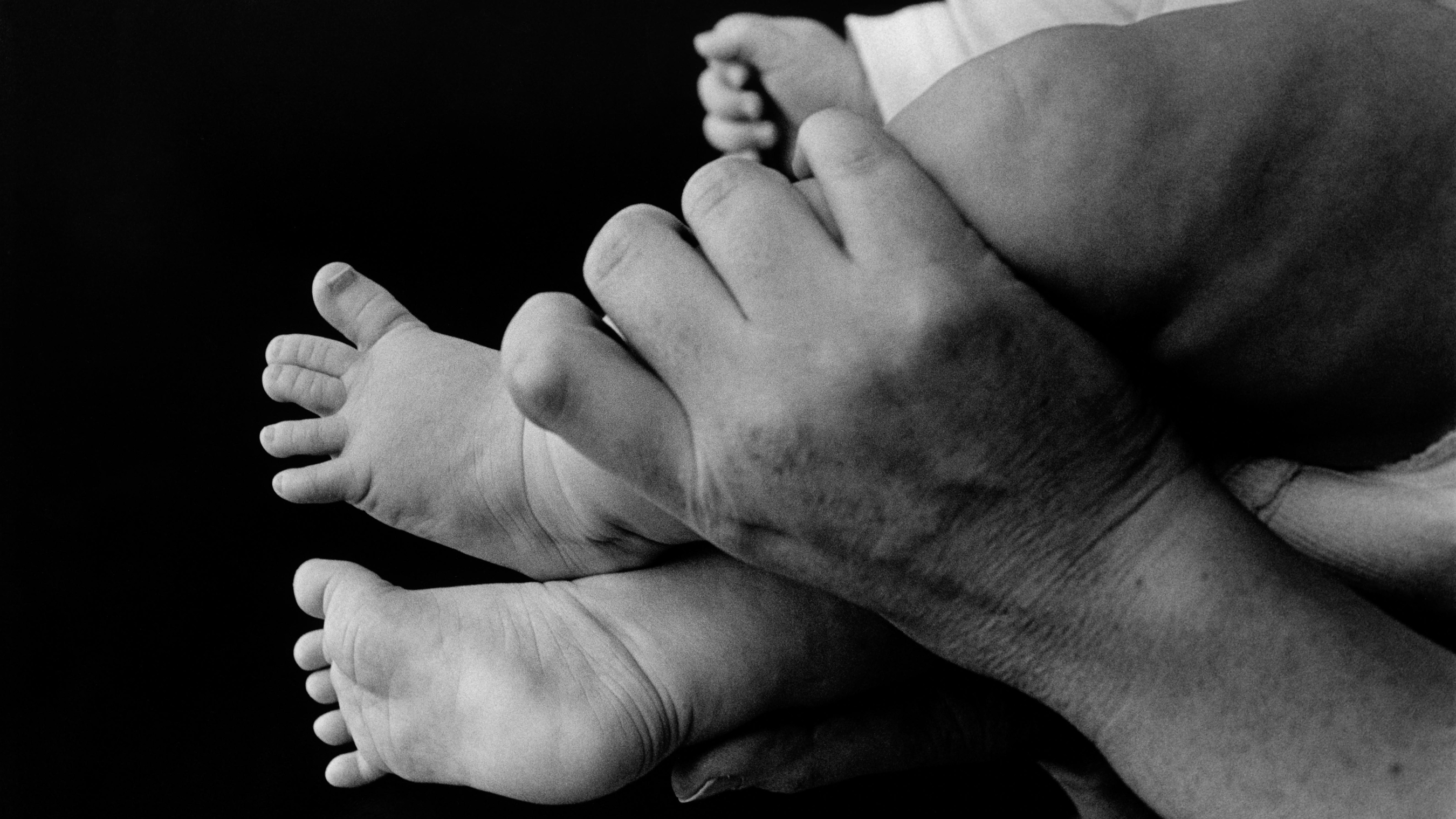 A hand holds a baby's leg