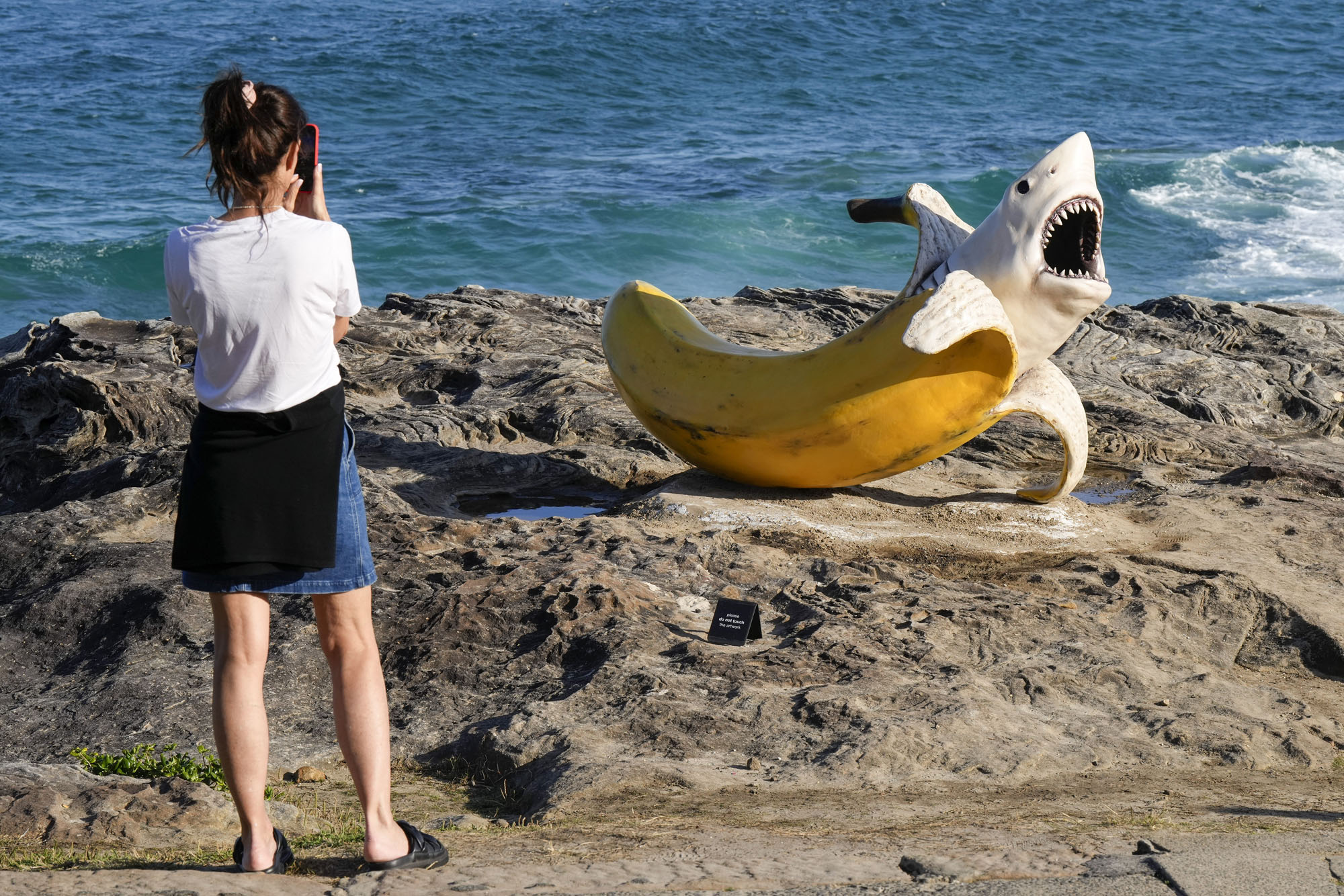 A woman photographs artwork from the “Sculpture by the Sea” exhibition at Bondi Beach.