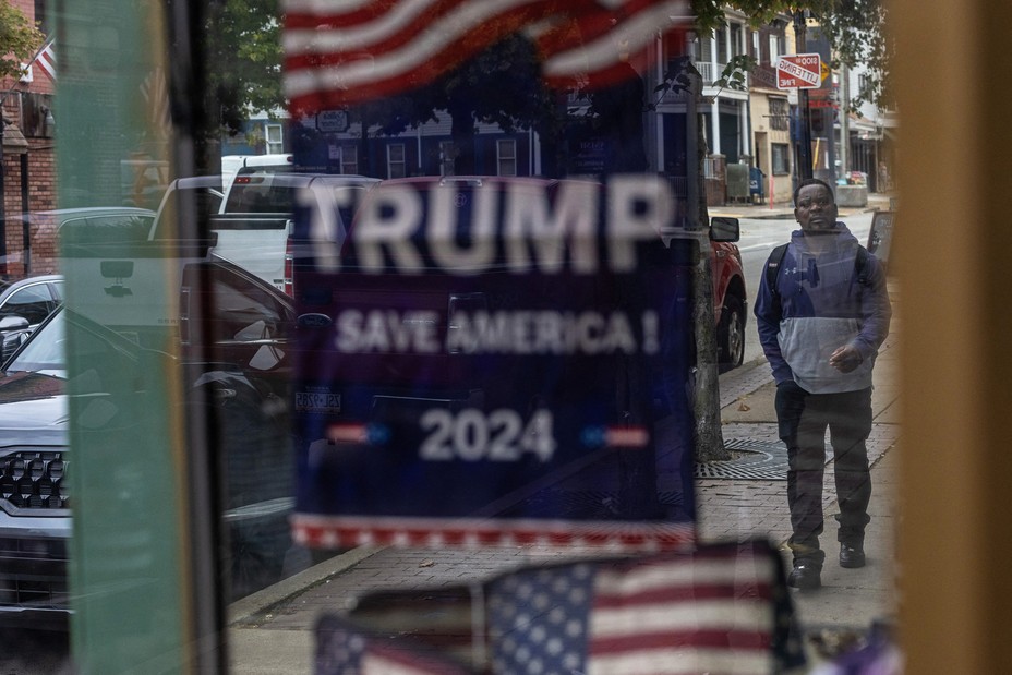 Picture of a campaign sign for Republican presidential nominee and former U.S. President Donald Trump is seen as an immigrant walks along a street in downtown Charleroi