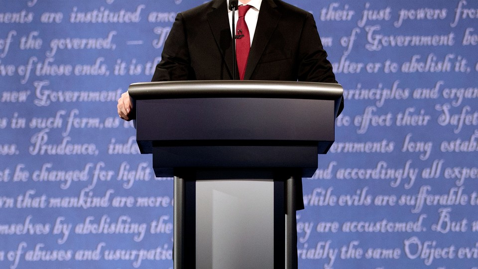 A politician's body at a lectern with words out of focus behind him.