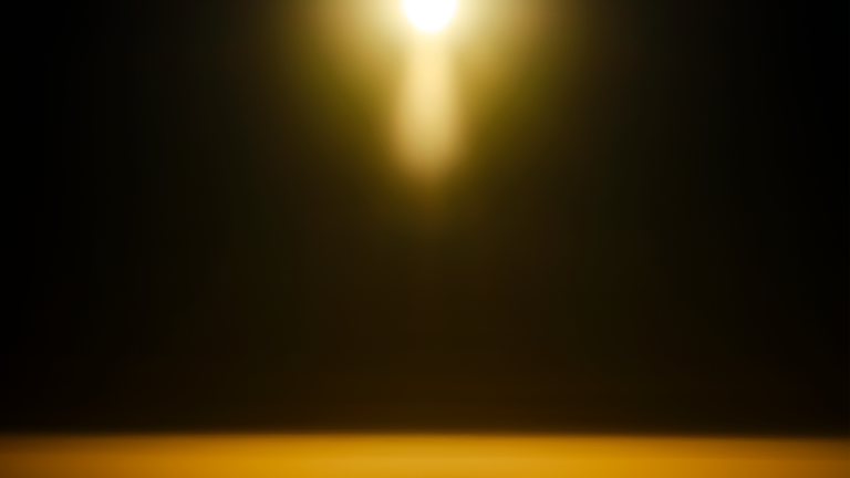 abstract photo of hazy moon-like light at top with golden halo on black background with golden horizon below