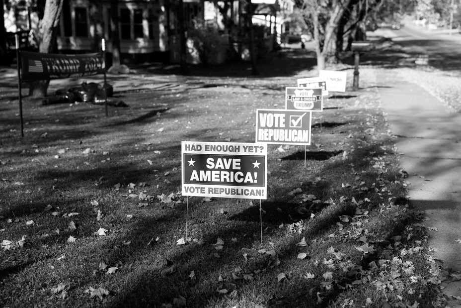 A black and white photo of election signs on a yard